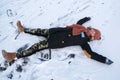 A happy teenage girl lies on the ice surface of a frozen lake on a Sunny winter day with her arms and legs outstretched and makes