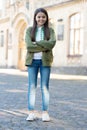 Happy teenage girl model kepping arms crossed in casual trendy style outdoors, fashion