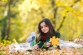 Happy teenage girl outdoor on the autumn field. Cute teenage girl lying on autumn maple leaves at fall outdoors Royalty Free Stock Photo