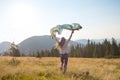 Happy teenage girl runs along the alpine meadow with a waving sc Royalty Free Stock Photo