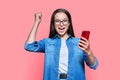 Happy teenage girl with smartphone, emotion yes success on red pink background Royalty Free Stock Photo