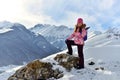 Happy teenage girl standing on a stone smiling in snowy mountains