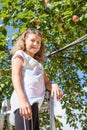 Happy teenage girl standing under apple tree with hanging apples Royalty Free Stock Photo