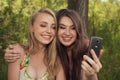 Happy teenage girls taking selfshot or selfy picture of themselves with mobile phone outdoors over green park Royalty Free Stock Photo