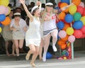 Happy teenage girls wearing graduation caps running out from sch