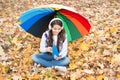 Happy teenage kid wearing earphones listen music and read book in autumn forest with beautiful seasonal nature under Royalty Free Stock Photo