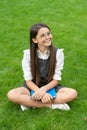 Happy teenage school girl sitting legs crossed on grass. School and education. Back to school Royalty Free Stock Photo