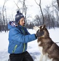 Happy teenager boy playing with white Husky dog in winter day, pet and child on snow Royalty Free Stock Photo