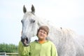 Happy teenager boy and white horse at the field Royalty Free Stock Photo