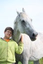 Happy teenager boy and white horse at the field Royalty Free Stock Photo