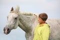 Happy teenager boy and white horse at the field Royalty Free Stock Photo