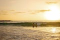 Happy teenager boys, running and playing on the beach on sunset, splashing water and jumping on the sand Royalty Free Stock Photo