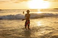 Happy teenager boys, running and playing on the beach on sunset, splashing water and jumping on the sand Royalty Free Stock Photo