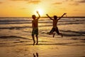 Happy teenager boys, running and playing on the beach on sunset, splashing water and jumping on the sand Royalty Free Stock Photo