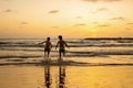 Happy teenager boys, running and playing on the beach on sunset, splashing water and jumping on the sand Royalty Free Stock Photo