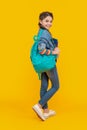 Happy teenager carrying backpack, education. Teenage girl yellow background. School education