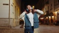 Happy teenager child girl kid in wireless headphones listening music dancing in night city street