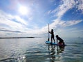 Happy teenager children in swimsuits  having fun on SUP board and  paddling in sea Royalty Free Stock Photo