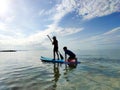 Happy teenager children in swimsuits  having fun on SUP board and  paddling in sea Royalty Free Stock Photo