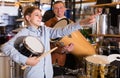 Teenager and father deciding on ethnic drum in musical shop