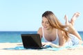 Happy teenager girl browsing social media in a laptop on the beach Royalty Free Stock Photo