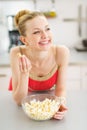 Happy teenager girl eating popcorn in kitchen Royalty Free Stock Photo