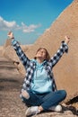 Happy Teenager girl in light blue hoodie and plaid shirt raising arms overhead