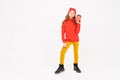 Happy teenager girl with red hair, red hat, hoody and yellow trousers smiles and drinks coffee isolated on white Royalty Free Stock Photo