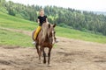 Happy teenager girl riding a horse on a mountainous area. The girl spends her leisure time with a smile. She likes this hobby Royalty Free Stock Photo