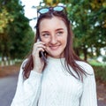 Happy teenager girl smiles and laughs, calls on phone, summer city park, background autumn trees. Emotions happiness are Royalty Free Stock Photo