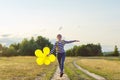 Happy teenager girl with balloons running and jumping along country road Royalty Free Stock Photo