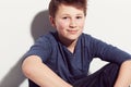 Happy, teenager and portrait of boy with fashion sitting in white background of studio. Cool, style and kid with a smile Royalty Free Stock Photo
