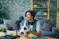 Happy teenager talking in microphone in recording studio holding football