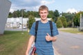 Happy teenager standing outside of a school building.