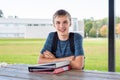 Happy teenager studying outdoors at a picnic table. Royalty Free Stock Photo