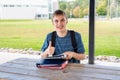 Happy teenager studying outdoors at a picnic table. Royalty Free Stock Photo