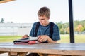 Happy teenager studying outdoors at a picnic table. Royalty Free Stock Photo