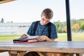 Happy teenager studying outdoors at a picnic table. Royalty Free Stock Photo