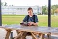 Happy teenager studying outdoors at a picnic table. Royalty Free Stock Photo