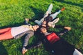 Happy teenagers lying head to head on their backs on the green grass