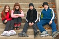 Happy teenagers in roller skates sitting outdoor