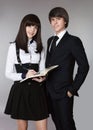 Happy teenagers in school uniform portrait. Handsome boy and beautiful brunette girl posing isolated on studio background. Royalty Free Stock Photo