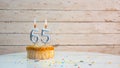 Happy 65th birthday greetings from silver numbers on white boards background copy space. Beautiful birthday card with a cupcake Royalty Free Stock Photo