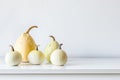 Happy Thanksgiving Background. Selection of various pumpkins on white shelf against white wall.