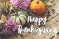 Happy Thanksgiving Card. Happy thanksgiving text on pumpkins, dahlias flowers, heather on rustic old wood. Season`s greetings, Royalty Free Stock Photo