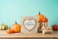 Happy Thanksgiving concept with photo frame, toy truck and pumpkin decor on wooden table over blue background. Autumn season