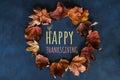 Happy thanksgiving day concept. Wreath of autumn leaves on a dark background with happy thanksgiving text. Royalty Free Stock Photo