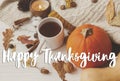 Happy Thanksgiving greeting card. Happy Thanksgiving text handwritten on warm tea, pumpkins, cozy knitted sweaters, autumn leaves Royalty Free Stock Photo
