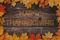 Happy Thanksgiving greeting text on wooden background with frame of maple leaves Royalty Free Stock Photo