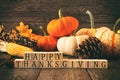 Happy Thanksgiving greeting against rustic wood with pumpkins and autumn decor. Vintage style.